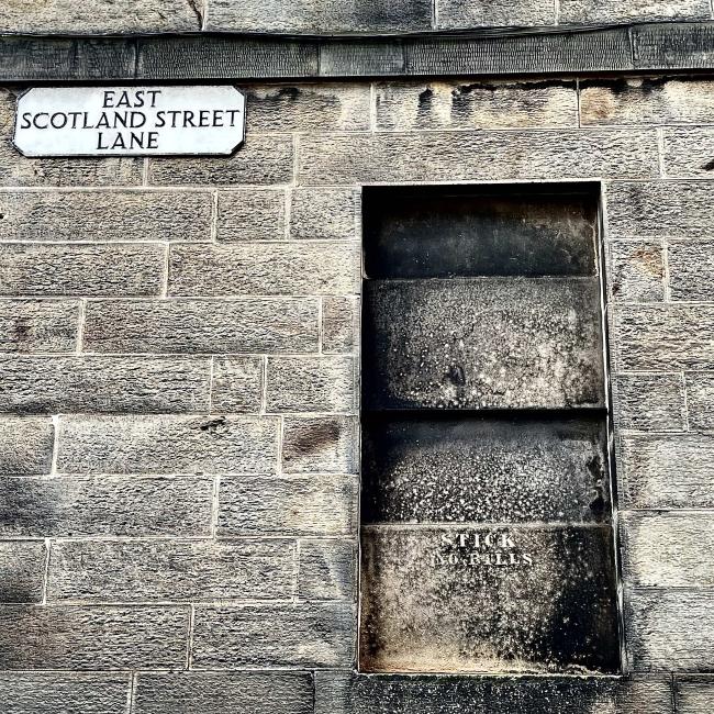 Gable-end masonry with a 'blind' window bearing an old hand-painted sign which reads 'Stick no bills.'