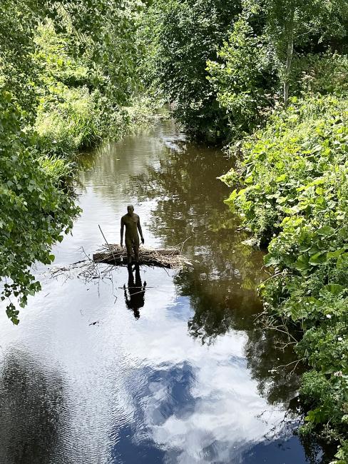 Gormley statue in Water of Leith, with debris building up behind it.